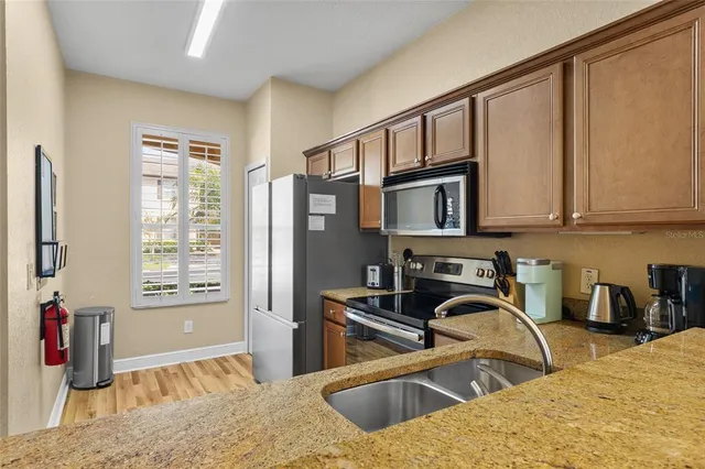 a kitchen with stainless steel appliances granite countertop a sink dishwasher stove and refrigerator with wooden floor