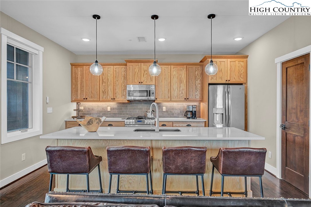 188 Ramblestone Terrace, Unit 101 Boone, NC 28607 - Photo 13 of 48 a kitchen with stainless steel appliances kitchen island granite countertop a dining table chairs and sink