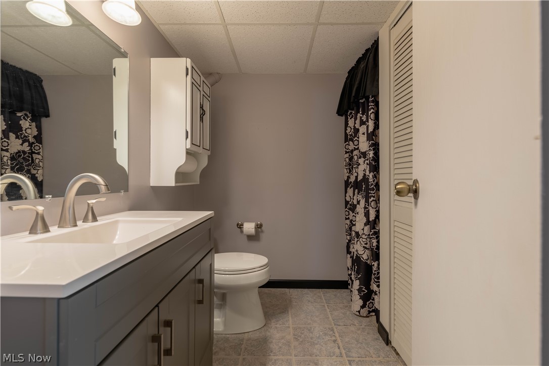3963 Mark Road Cambridge, OH 43725 - Photo 37 of 50 Bathroom with tile flooring, vanity, toilet, and a drop ceiling
