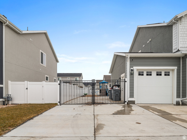 627 South Meade Street Mapleton, UT 84664 - Photo 18 of 48 Concrete driveway with a black wrought iron gate, white vinyl fencing, and an attached garage featuring a white door with transom windows
