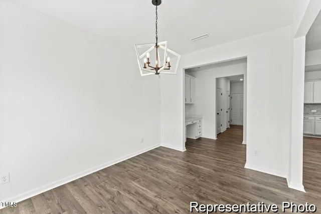 a view of a hallway with wooden floor and a chandelier