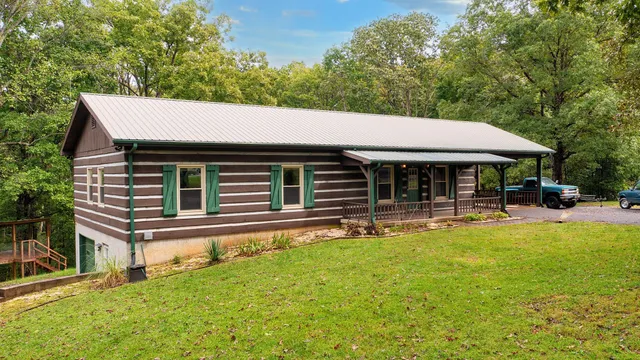 a backyard of a house with table and chairs under an umbrella