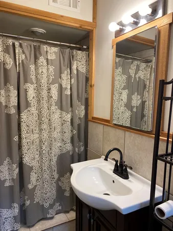 a bathroom with a sink and mirror with bathtub