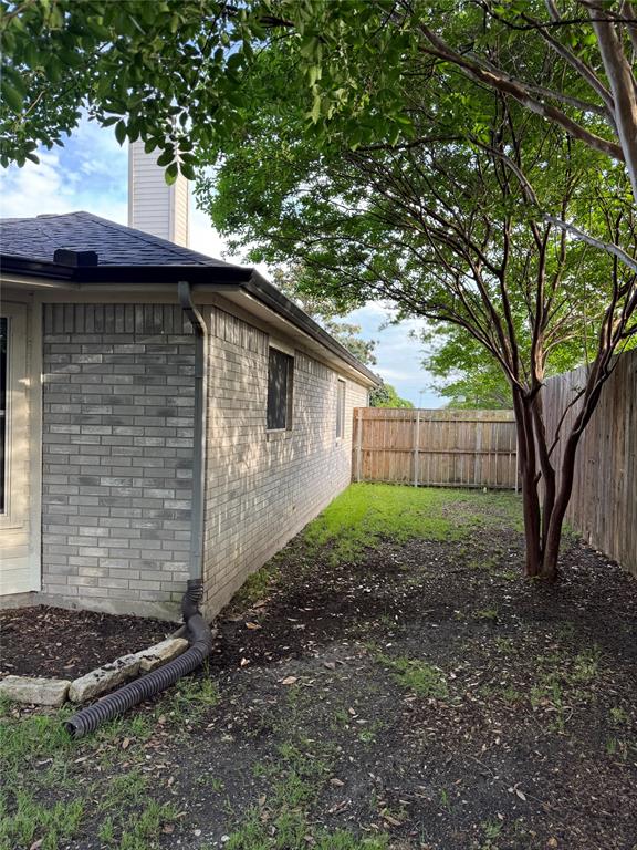 6241 Peach Tree Drive Midlothian, TX 76065 - Photo 17 of 19 Private side yard featuring a partial brick exterior, mature trees, and wood fencing