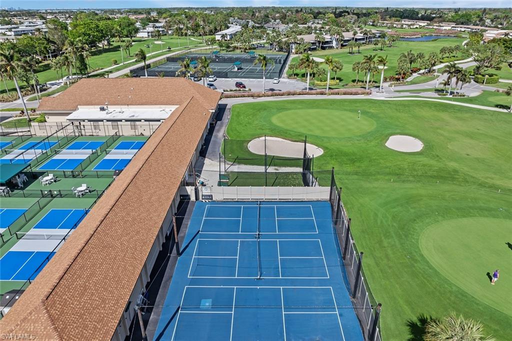 136 Harrison Road, Unit 1 Naples, FL 34112 - Photo 23 of 29 Expansive property featuring multiple blue-surfaced pickleball courts, a large blue-surfaced tennis court, and a meticulously maintained golf course with sand traps