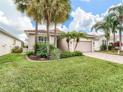 front view of house with a yard and palm trees