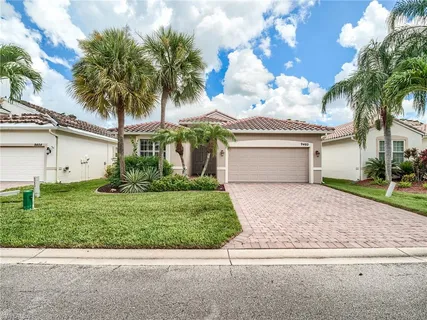 front view of a house with a yard and palm trees