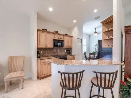 a kitchen with stainless steel appliances kitchen island granite countertop a kitchen island and chairs in it