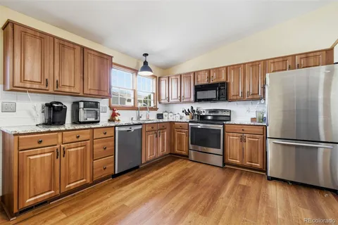 a kitchen with granite countertop a refrigerator stove top oven and sink