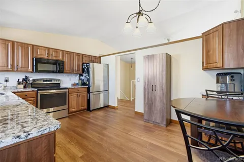 a kitchen with stainless steel appliances granite countertop a refrigerator a stove top oven a sink dishwasher and wooden cabinets with wooden floor