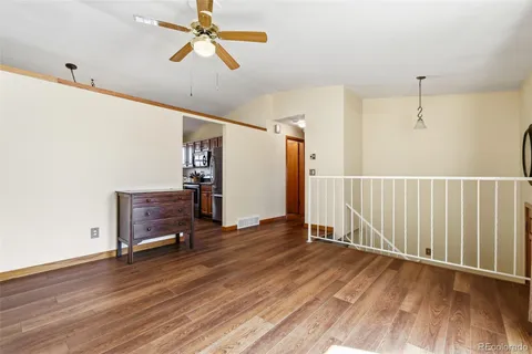 a view of a room with wooden floor stairs and a chandelier fan