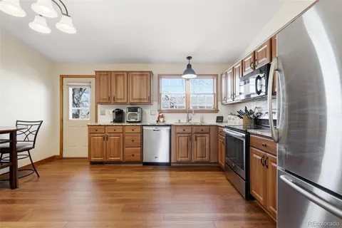 a kitchen with stainless steel appliances granite countertop a stove a sink dishwasher and a refrigerator with wooden floor