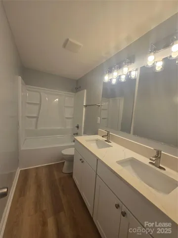 a bathroom with a double vanity sink and mirror with toilet