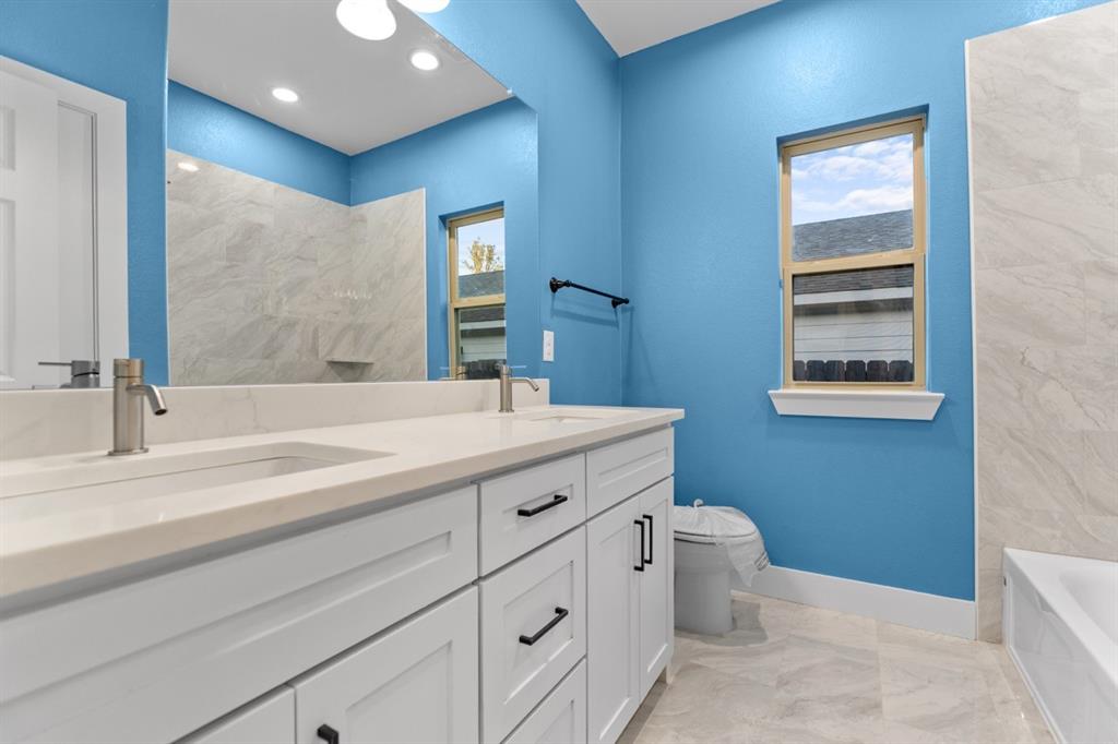 520 East 5th Street Bonham, TX 75418 - Photo 9 of 16 a bathroom with a double vanity sink a toilet and mirror