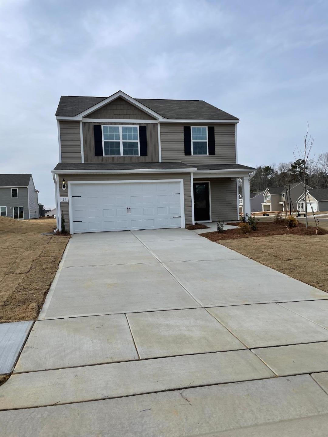 a front view of a house with yard and parking