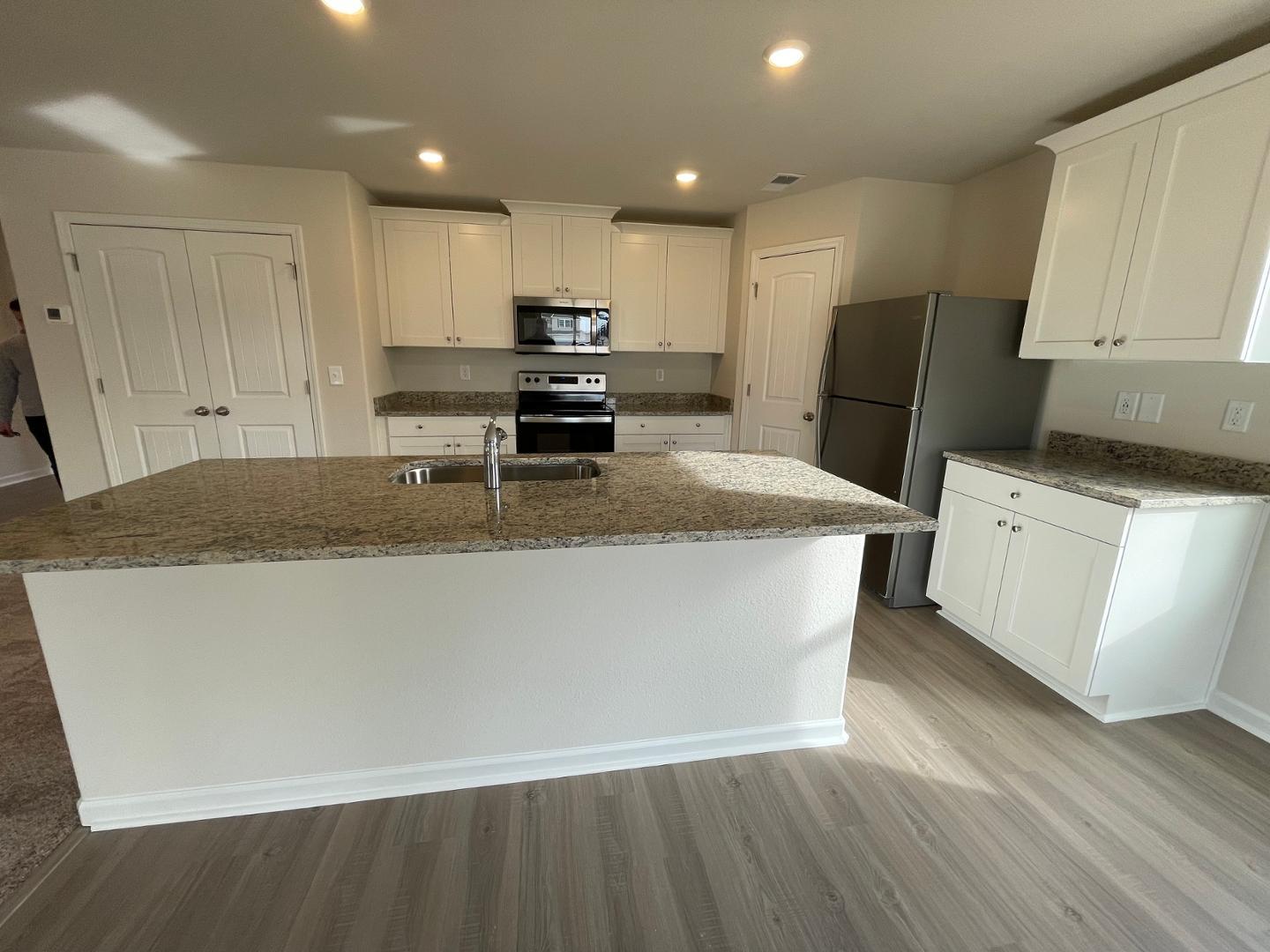 111 Hybrid Street Oxford, NC 27565 - Photo 5 of 25 a kitchen with stainless steel appliances granite countertop a sink a stove a refrigerator a microwave oven with white cabinets and wooden floor