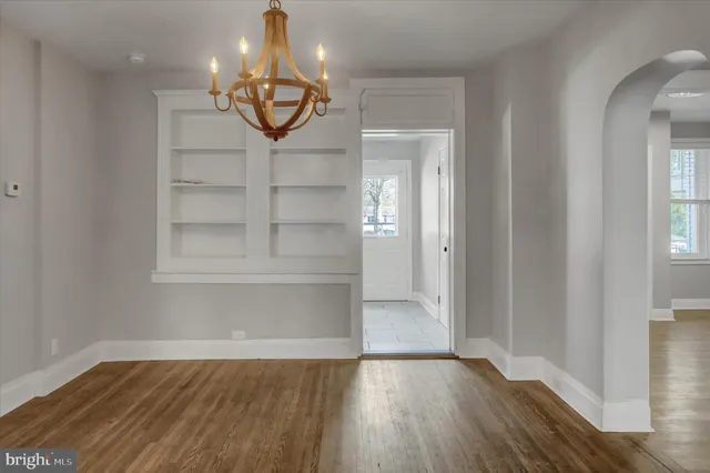 an empty room with wooden floor mirror and windows