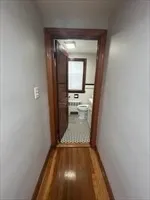 a view of a hallway with wooden floor and a bathroom
