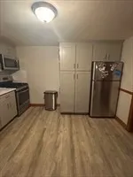 a view of a refrigerator in kitchen and an empty room