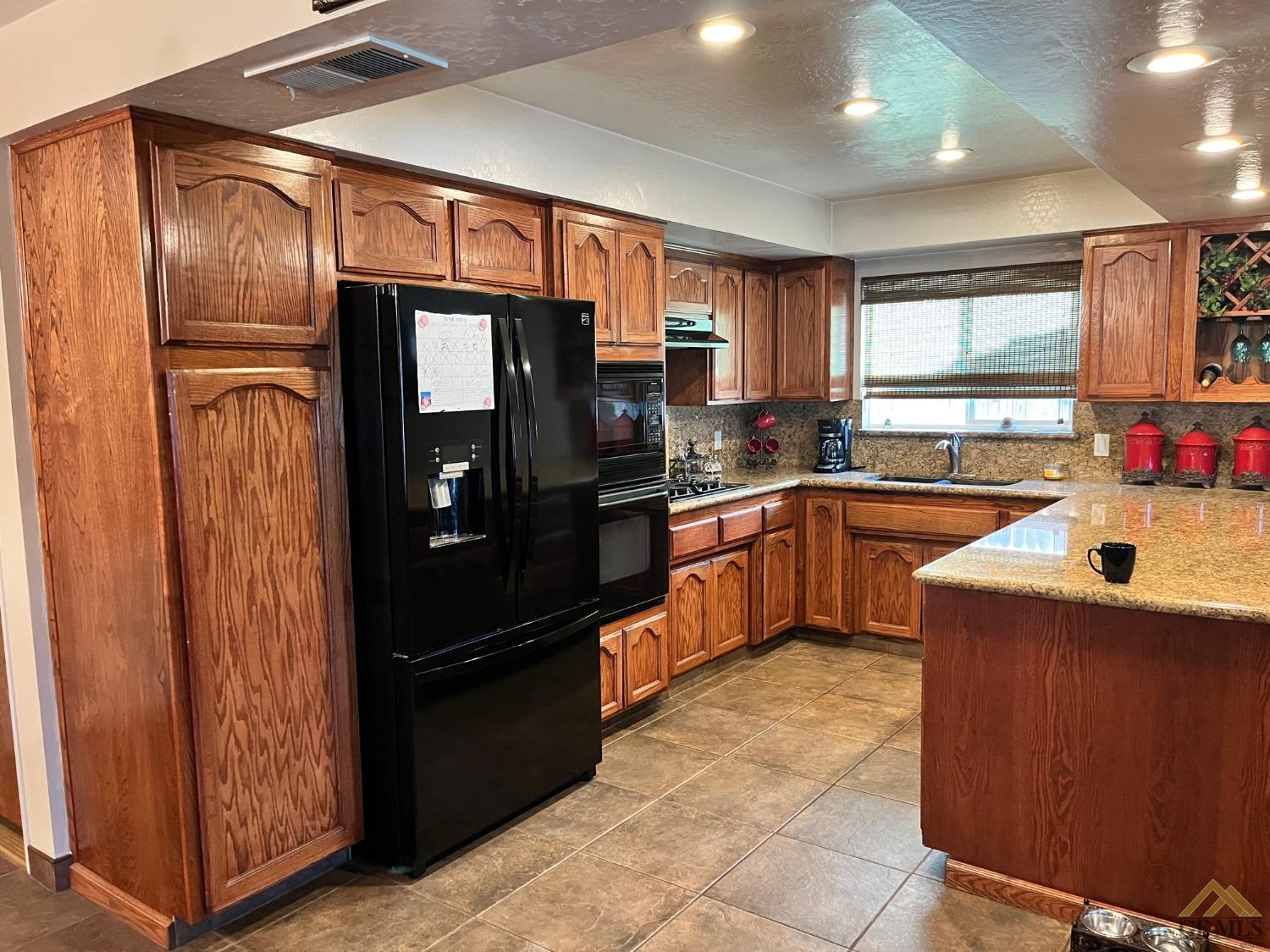 Undisclosed Address Bakersfield, CA 93309 - Photo 5 of 28 a kitchen with granite countertop stainless steel appliances and wooden cabinets
