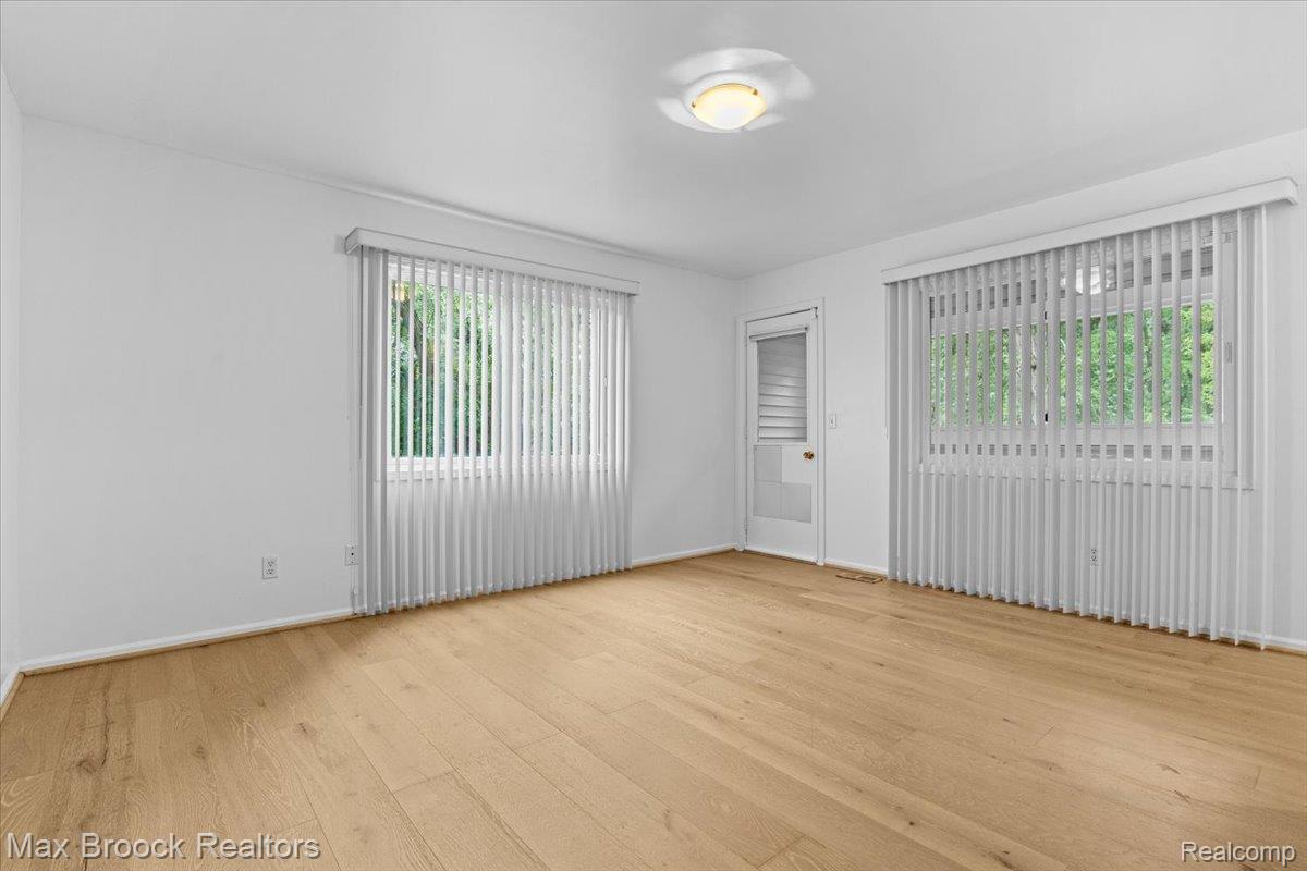1830 Lone Pine Road Bloomfield Hills, MI 48302 - Photo 45 of 70 Wood-finish flooring with white baseboards, two windows with vertical blinds, a white door with a window, and a ceiling-mounted light fixture