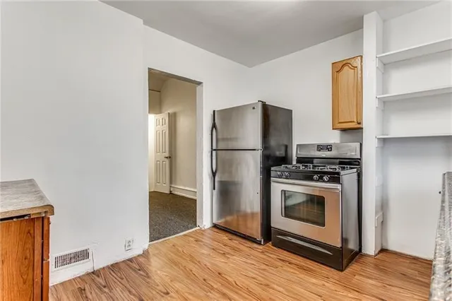 a kitchen with a refrigerator stove and wooden floor