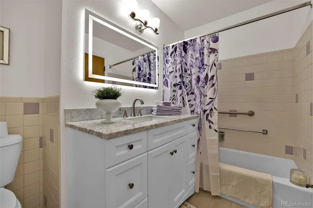 a bathroom with a granite countertop sink a toilet and shower