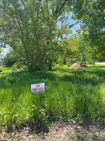 a sign that is sitting in the grass next to a tree
