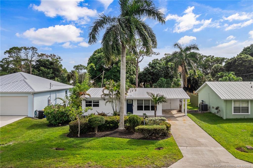 3156 Southeast Mimosa Street Stuart, FL 34997 - Photo 3 of 38 a front view of a house with a garden