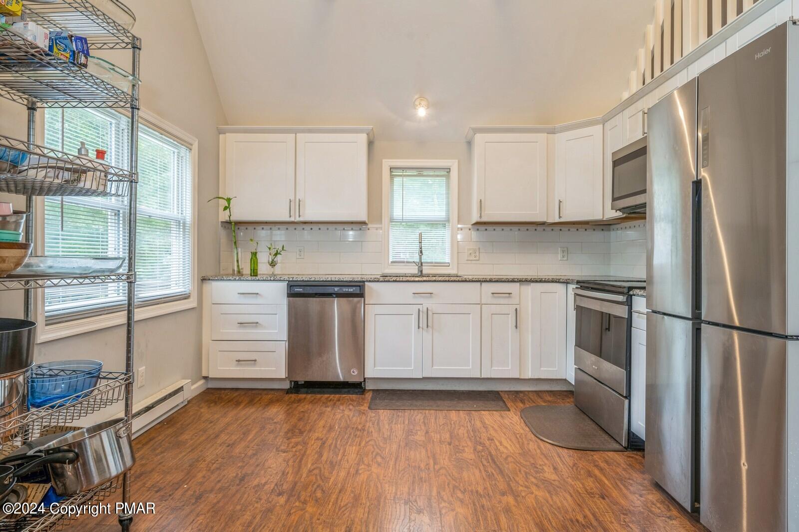 104 Swan Drive Dingmans Ferry, PA 18328 - Photo 10 of 36 a kitchen with a refrigerator wooden floor and white cabinets