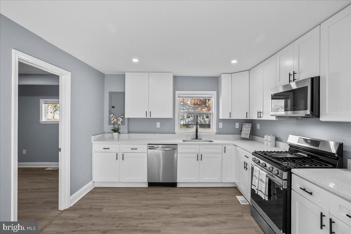 57 Transverse Avenue Middle River, MD 21220 - Photo 25 of 35 a kitchen with stainless steel appliances granite countertop a stove top oven a sink dishwasher and a refrigerator with wooden floor