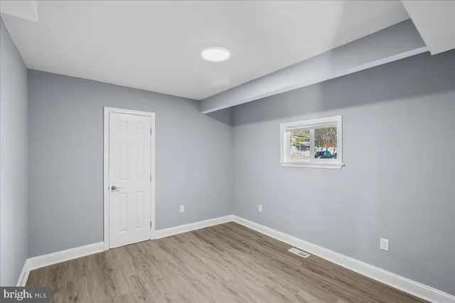 an empty room with wooden floor and window