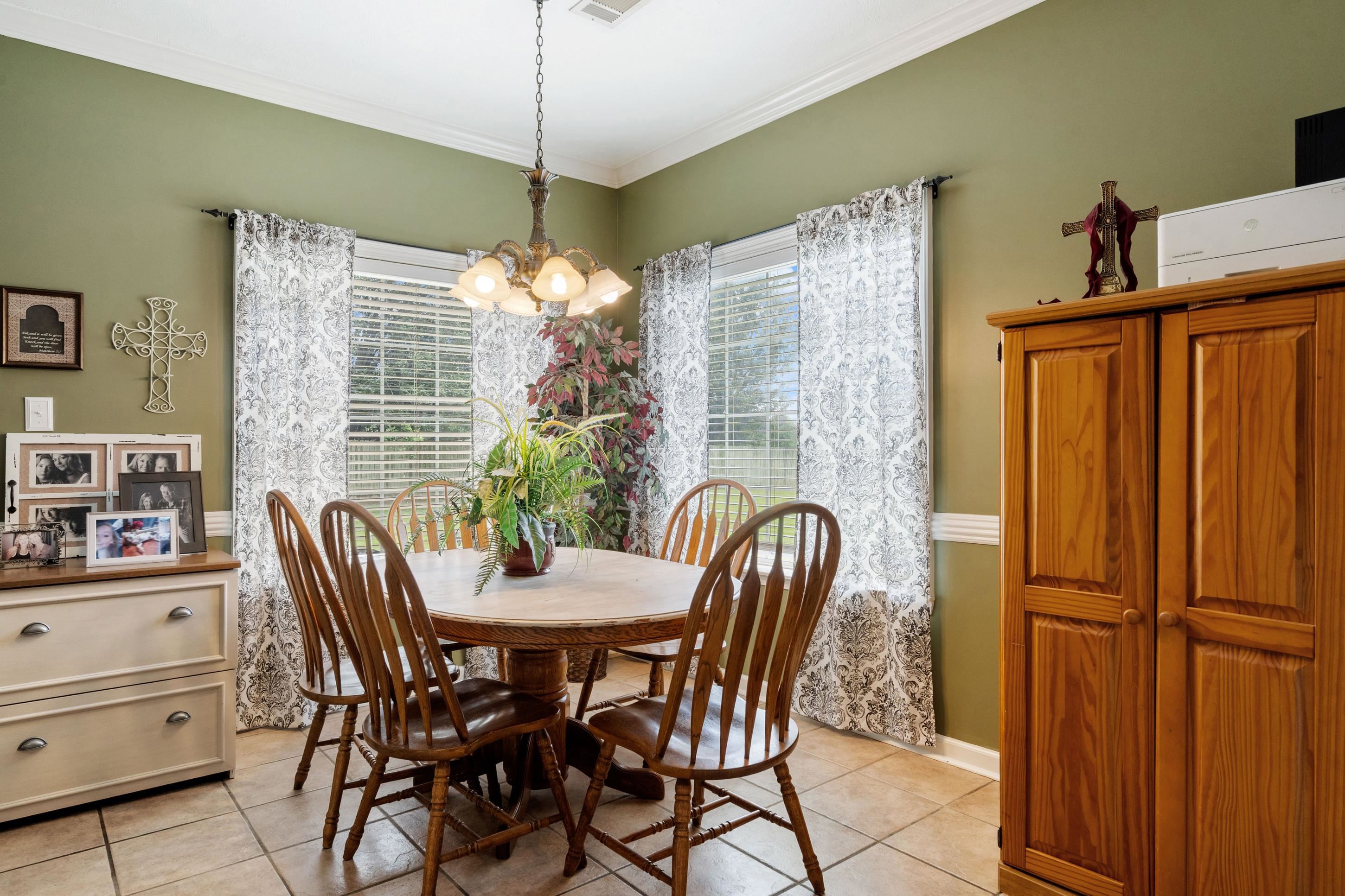 7757 Brunswick Road Millington, TN 38053 - Photo 10 of 40 Dining area featuring tile flooring, a window with blinds and patterned curtains, a chandelier, and crown molding