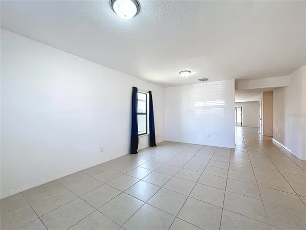 a view of an empty room with window and chandelier fan