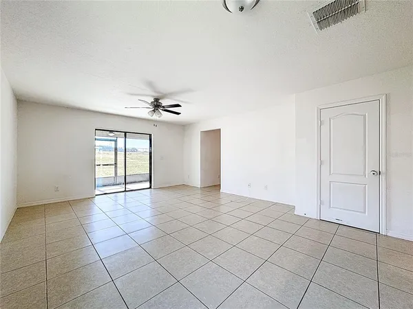 an empty room with windows and ceiling fan