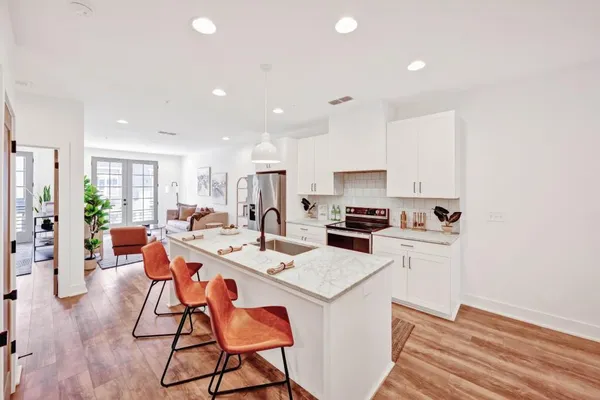 a kitchen with a dining table chairs stove and white cabinets