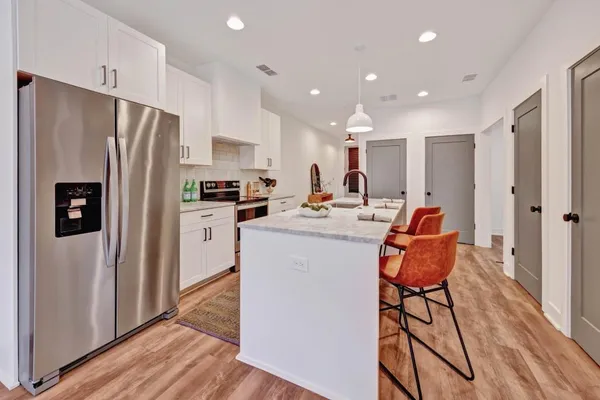a kitchen with stainless steel appliances a refrigerator a stove top oven and wooden floor