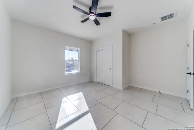 an empty room with windows and ceiling fan