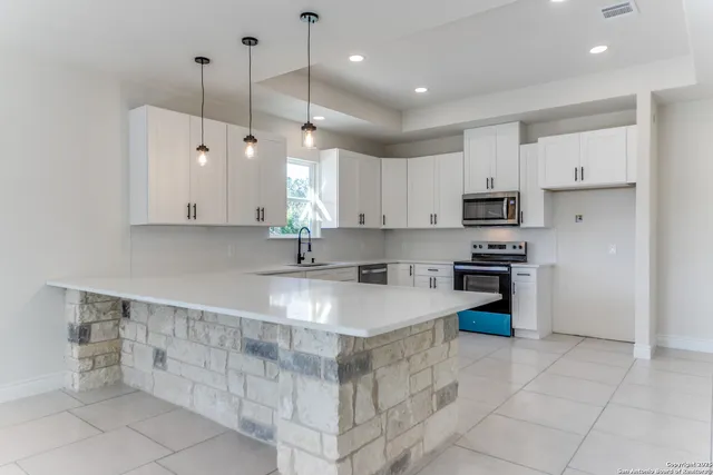 a large kitchen with stainless steel appliances granite countertop a sink a stove and a refrigerator