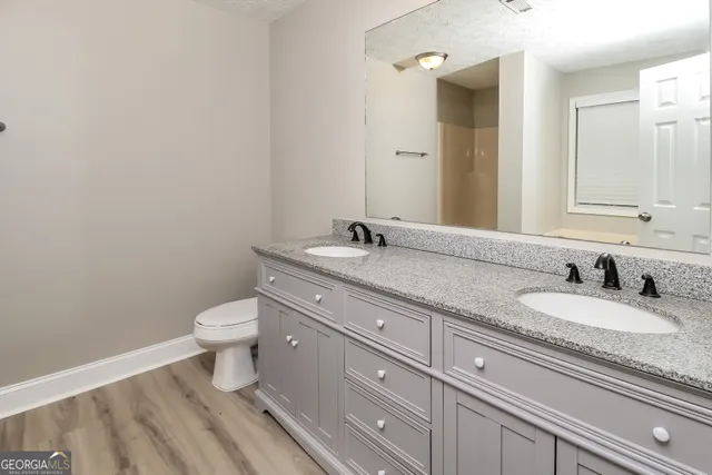 a bathroom with a granite countertop toilet sink and mirror