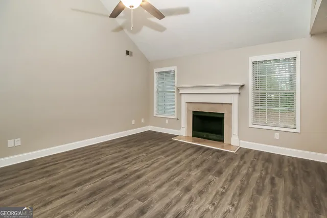 a view of an empty room with wooden floor fireplace and a window