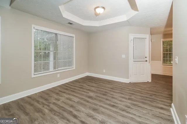 a view of an empty room with wooden floor and a window