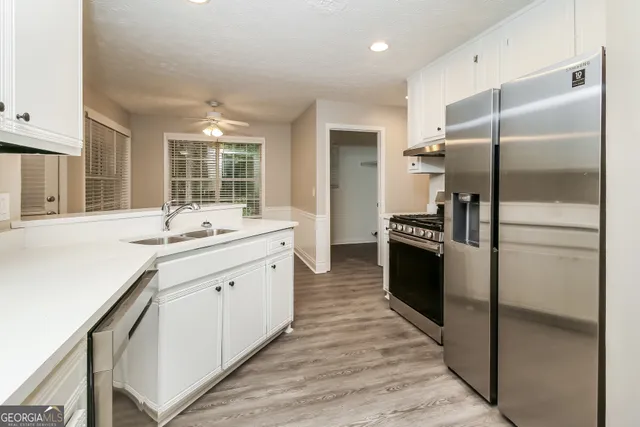 a modern kitchen with stainless steel appliances kitchen island granite countertop a refrigerator and a sink