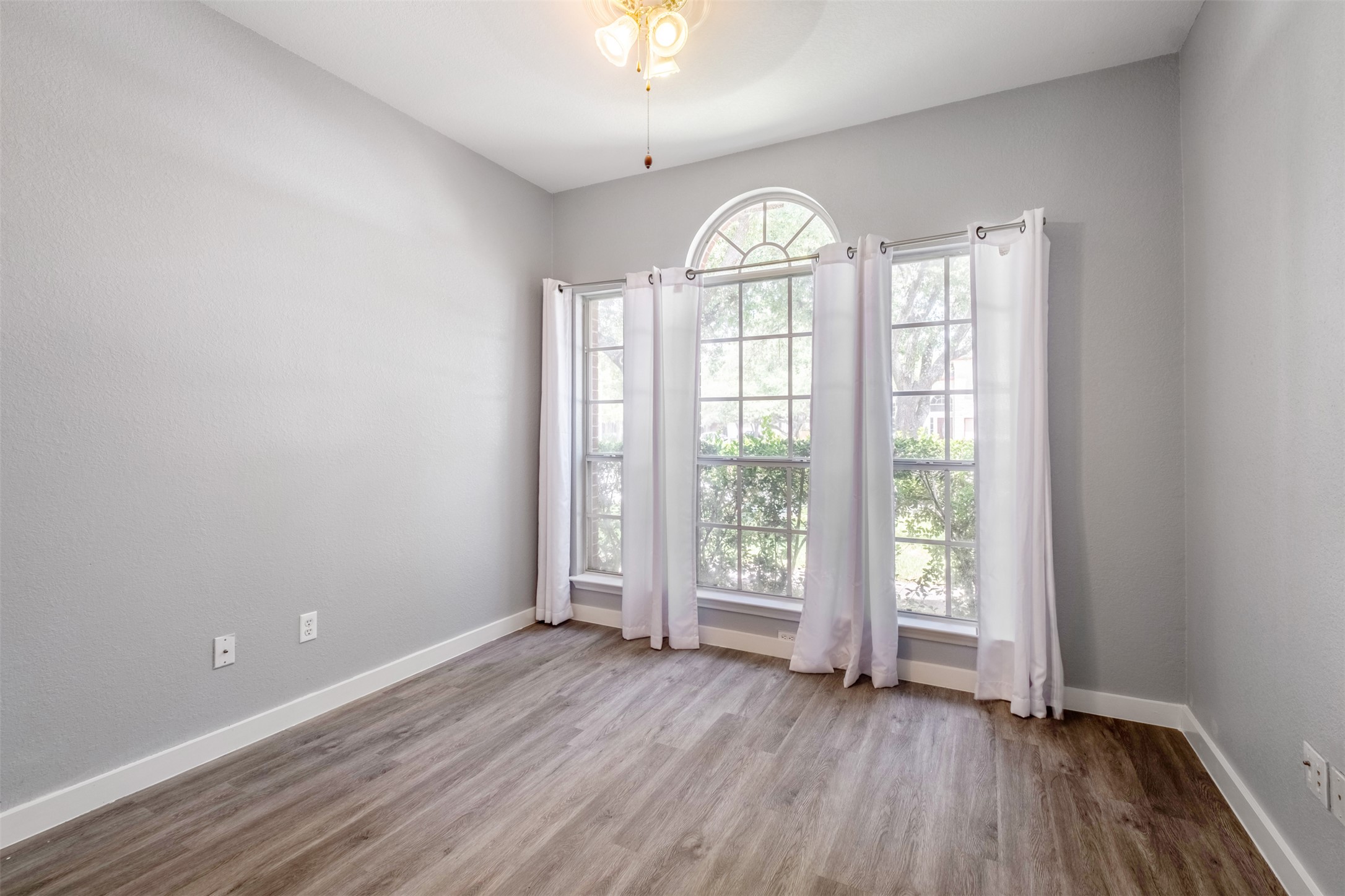 3413 Ruby Red Drive Austin, TX 78728 - Photo 17 of 19 A well-lit room features an arched window above two large rectangular windows, complemented by light wood flooring.