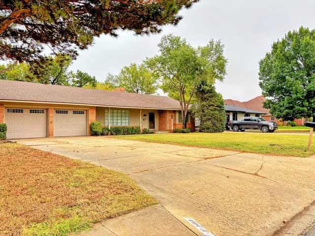 a view of a house with a yard and large trees