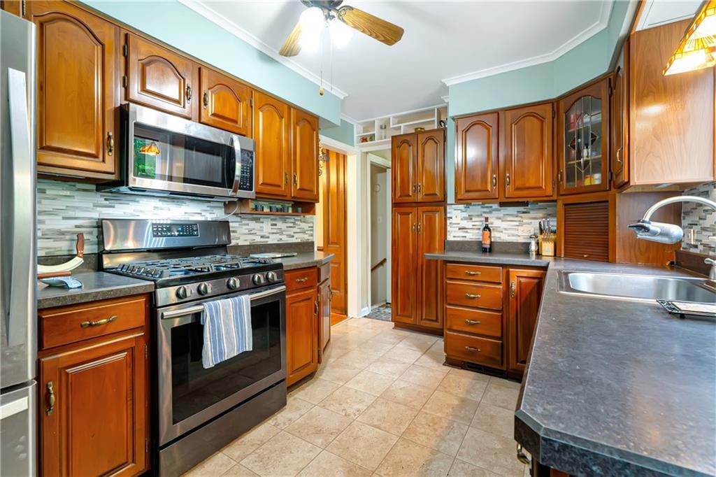 166 Spring Grove Road Pittsburgh, PA 15235 - Photo 16 of 41 a kitchen with stainless steel appliances granite countertop a stove top oven a sink dishwasher a dining table and chairs with wooden floor