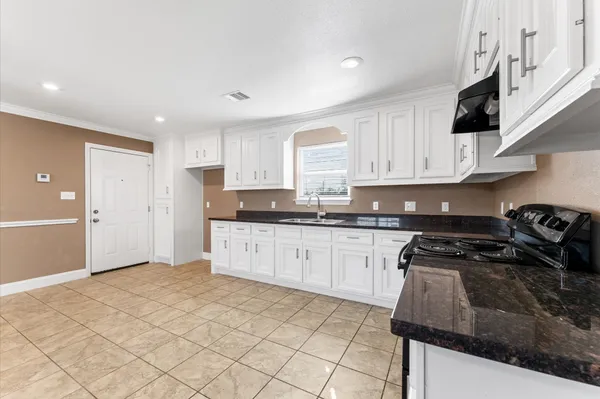 a kitchen with granite countertop a stove sink and cabinets