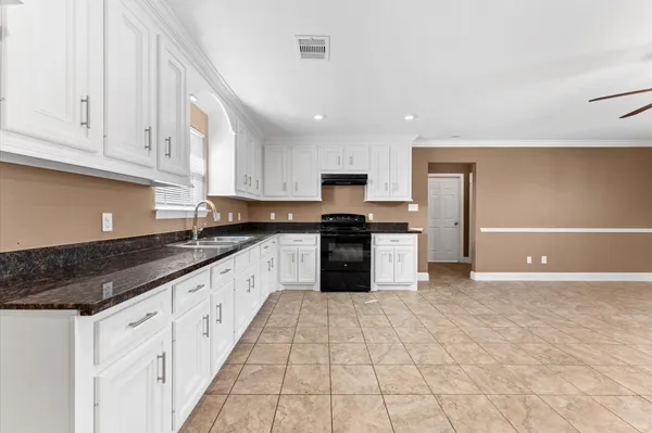 a large kitchen with granite countertop a stove a sink dishwasher and a refrigerator with wooden floor