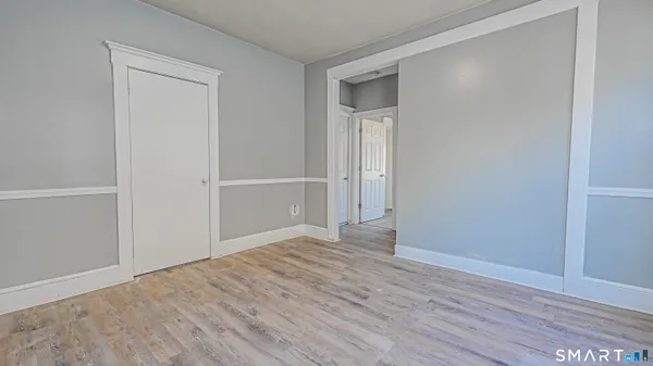 a view of an empty room with wooden floor and closet