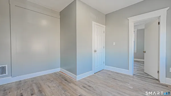 a view of an empty room with wooden floor and closet